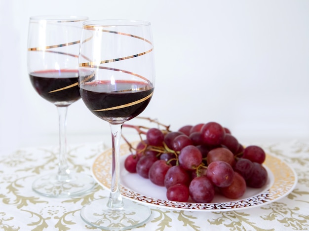 Dwie szklanki czerwonego wina z kiści czerwonych winogron