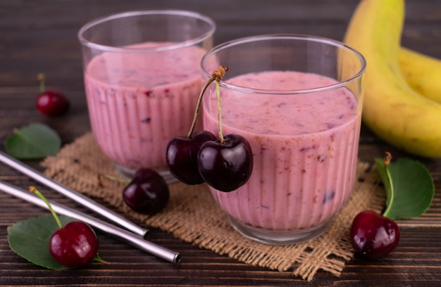 Dwie szklanki koktajlu wiśniowo-bananowego na ciemnym drewnianym tle