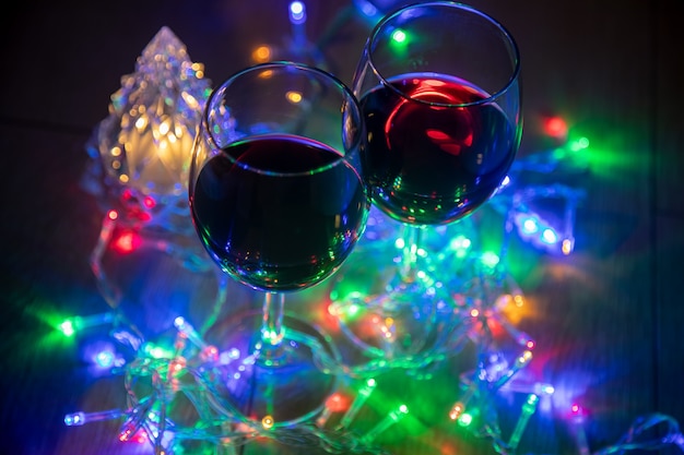 dwie szklanki na tle świecącej choinki i wielokolorowa girlanda na ciemnym tle nocy. Obchody Nowego Roku...