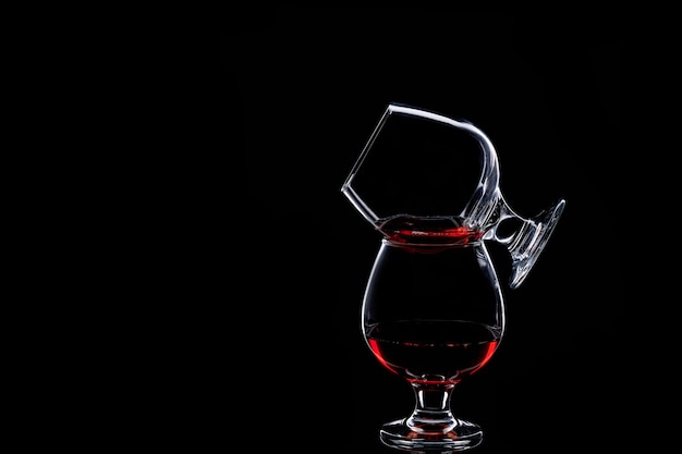 Dwie szklanki sylwetka z czerwonego wina na czarnym tle