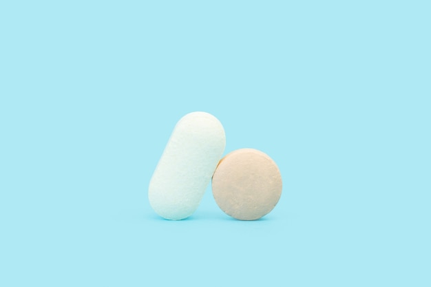 Dwie tabletki medyczne na jasnoniebieskim tle w widoku z przodu