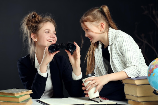 Dwie uczennice patrzące przez lornetkę Książki i tablica szkolna Koncepcja edukacyjna