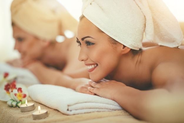Dwie urocze młode kobiety cieszą się podczas zabiegu pielęgnacji skóry w spa.