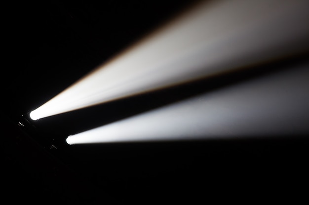 Zdjęcie dwie wiązki reflektorów w ciemnej sali koncertowej.