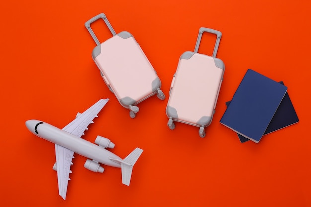 Dwie zabawki bagaż podróżny, samolot i paszport na pomarańczowo. Planowanie podróży