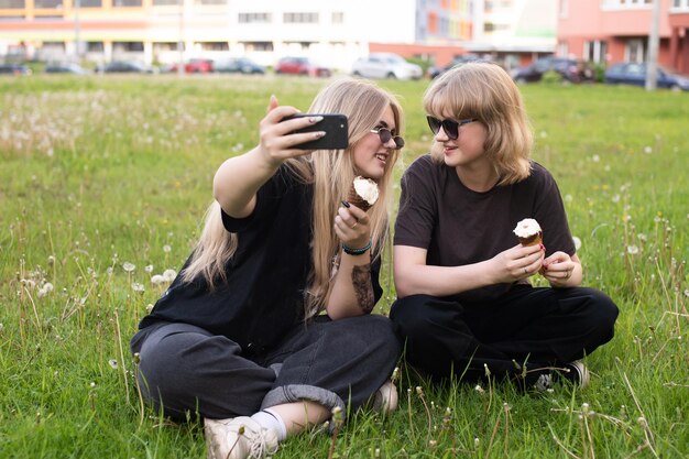 Dwie zabawne dziewczyny jedzą lody i robią sobie selfie na ulicy Nastolatki w sieciach społecznościowych