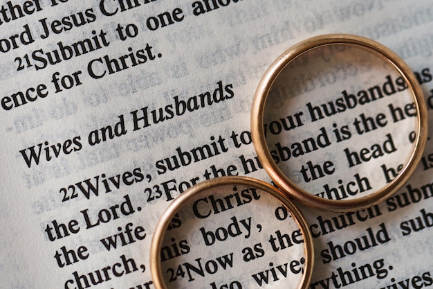 Dwie złote obrączki i otwarte strony Pisma Świętego reprezentują koncepcję małżeństwa i miłości między dwoma chrześcijanami