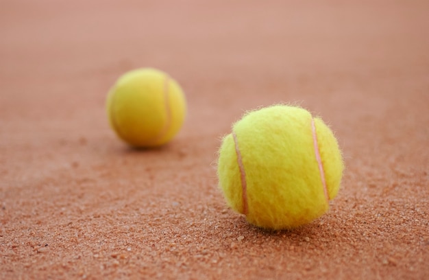 Dwie żółte piłki tenisowe na podłodze kortu ceglanego