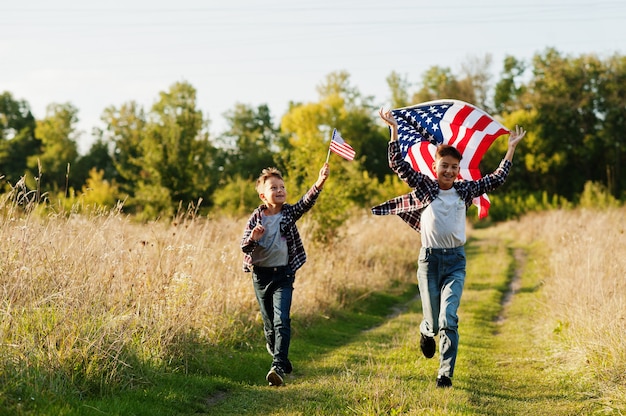 Dwóch braci biegnących z flagą USA. Święto Ameryki. Dumni, że są dziećmi kraju.