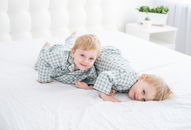 Dwóch Braci Szczęśliwych Chłopców Na Białym łóżku W Piżamie, Wspólna Zabawa