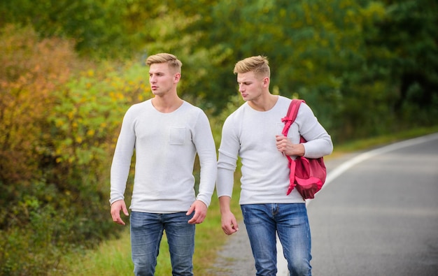 Dwóch Braci Wyrusza Na Przygodę. Koncepcja Przyjaźni. Mężczyźni łapią Piesze Wędrówki. Mężczyzna Dorywczo Styl Podróży Z Plecakiem. Podróżnik Autostop Na Autostradzie. W Drodze Do Domu. Przyszły. Bliźnięta Idące Wzdłuż Drogi.