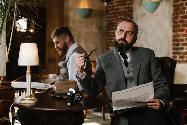 Zdjęcie dwóch brodatych mężczyzn w staromodnych garniturach rozmawia lub rozmawia o czymś w restauracji