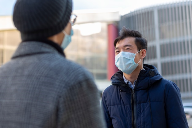 Dwóch chińskich mężczyzn w medycznych maskach ochronnych przed rozmową Covid-2019