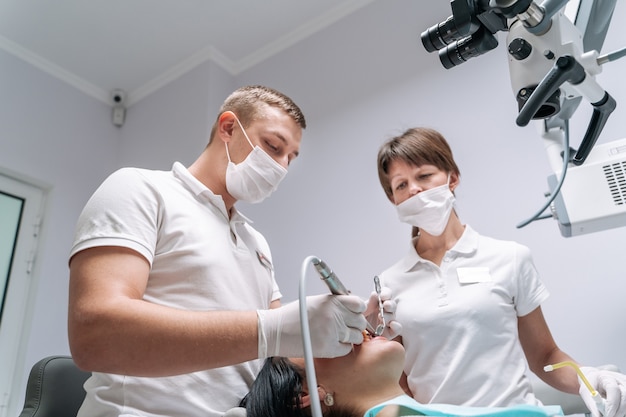 Dwóch dentystów bada zęby pacjenta do zabiegu.
