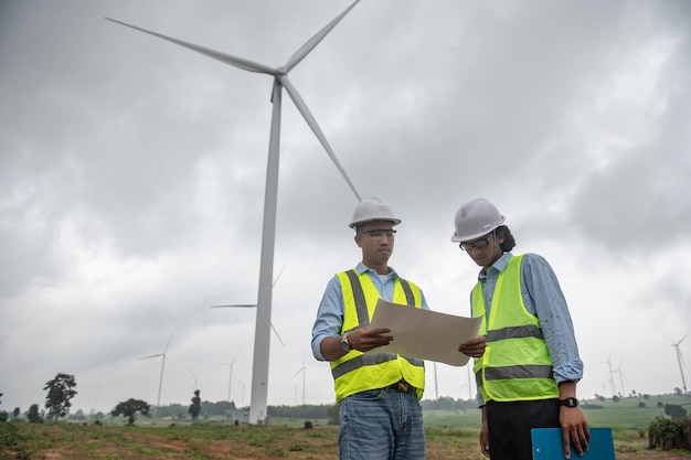 Dwóch inżynierów pracujących i trzymających raport na farmie turbin wiatrowych Power Generator Station na górskiej ludności Tajlandii