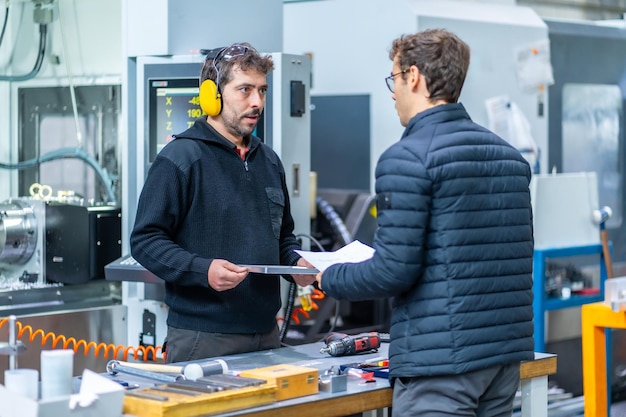 Dwóch inżynierów rozmawiających podczas badania elementów w fabryce CNC
