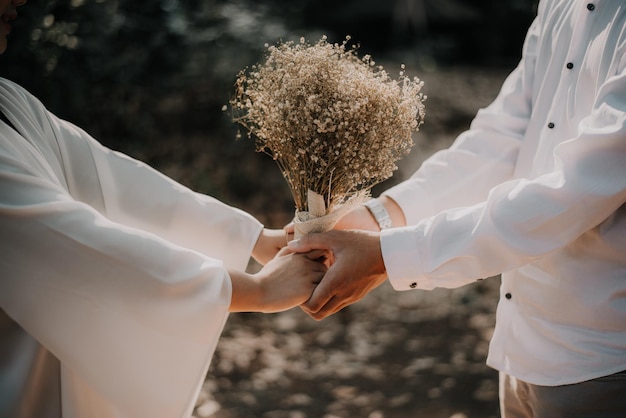Zdjęcie dwóch kochanków trzymających suszony kwiat w ręku, aby pokazać swoją miłość i przywiązanie
