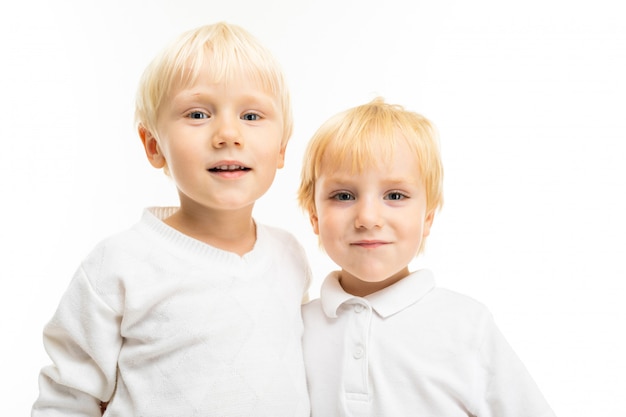 Dwóch małych braci kaukaskich z blond włosami i jasnymi czerwonymi włosami, portret na białym tle