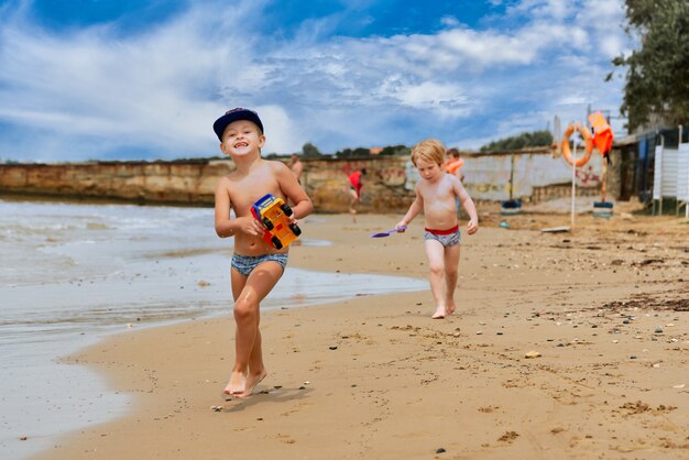 Dwóch małych chłopców bawi się na brzegu morza