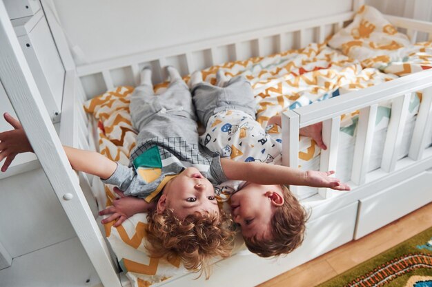Zdjęcie dwóch małych chłopców odpoczywa i bawi się razem w sypialni