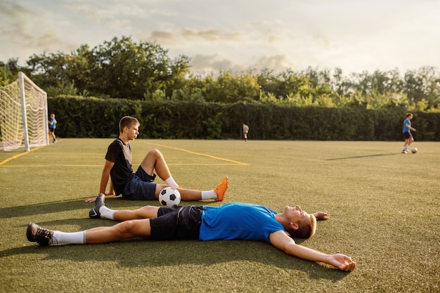 Dwóch mężczyzn piłkarzy na trawie na boisku. Piłkarze na stadionie zewnętrznym, trening przed meczem, trening piłkarski