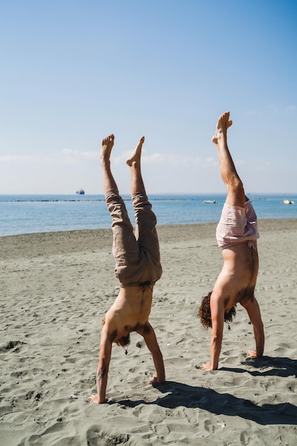 Dwóch mężczyzn robi stanie na rękach dla siły i równowagi na plaży