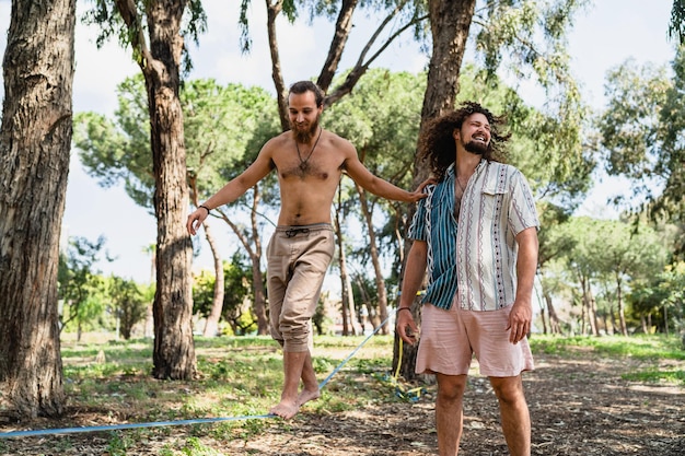 Dwóch mężczyzn slacklining w parku miejskim w letni dzień