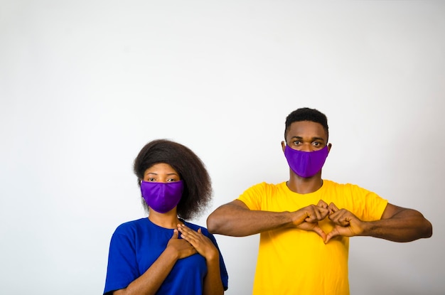 Dwóch młodych afrykańskich studentów izolowanych na białym tle noszących maskę na twarz, aby zapobiec wybuchowi epidemii w społeczeństwie