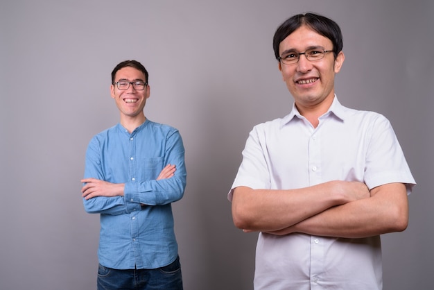 Dwóch Młodych Biznesmenów Azjatyckich Razem Noszenie Okularów Przeciw Szarej ścianie