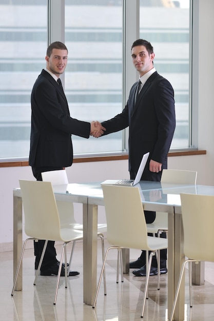 dwóch młodych biznesmenów uścisk dłoni na spotkaniu biznesowym w nowoczesnym biurze i reprezentujący sukces