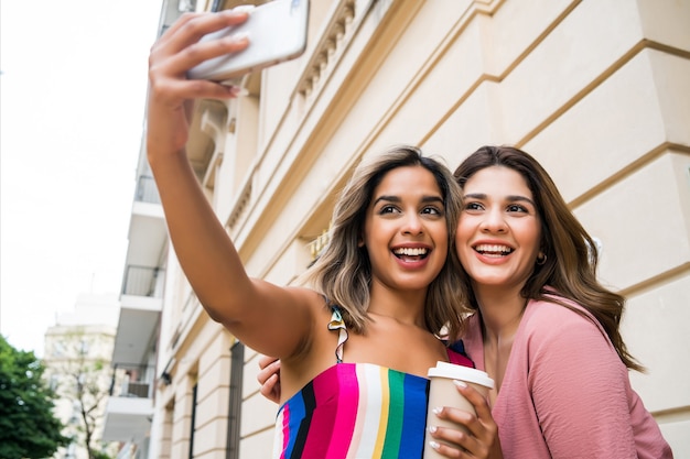 Dwóch Młodych Przyjaciół Uśmiecha Się I Robi Selfie Z Telefonem Komórkowym, Stojąc Na Zewnątrz