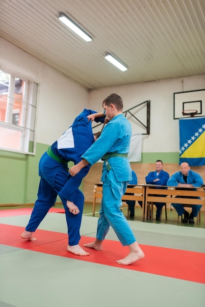 Dwóch młodych sportowców pokazuje swoje umiejętności judo przed trenerami