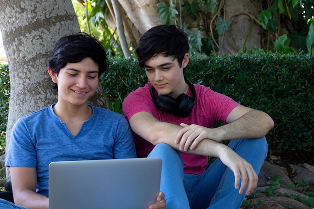 Dwóch młodych studentów ogląda laptopa siedząc w parku