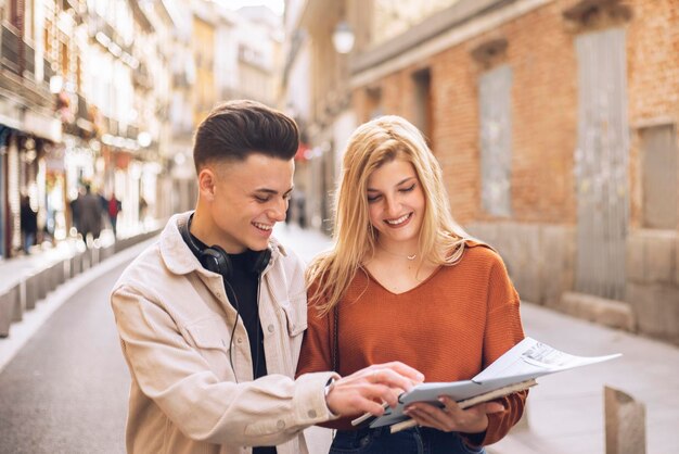 Zdjęcie dwóch młodych studentów przegląda notatki z college'u podczas spaceru po mieście