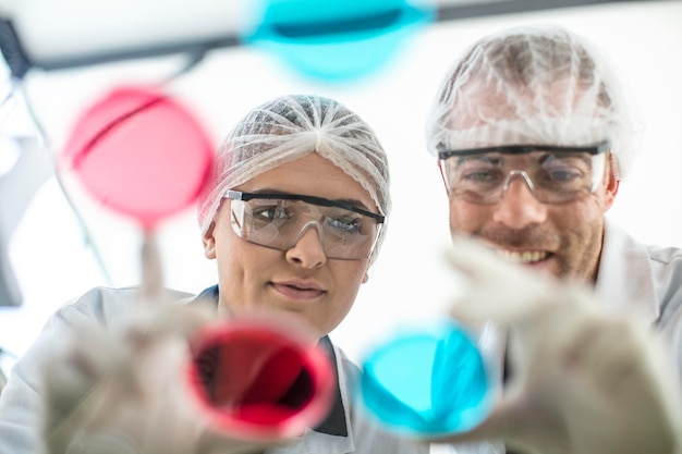 Zdjęcie dwóch naukowców pracujących razem w laboratorium, patrząc na szalki petriego