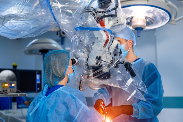 Dwóch neurochirurgów w nowoczesnej klinice korzysta z mikroskopu operacyjnego. kompleksowa obsługa przy użyciu najnowocześniejszego sprzętu. Zbliżenie.