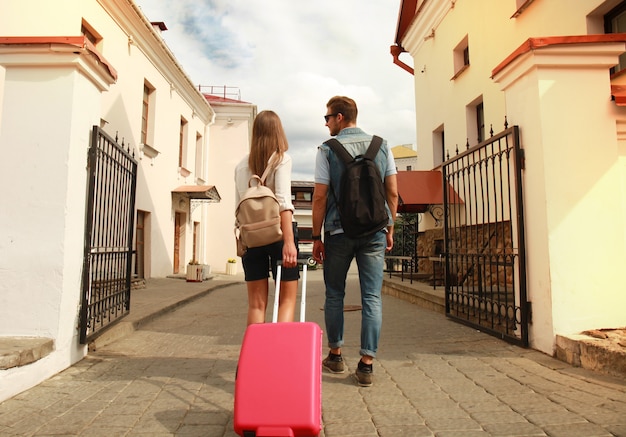 Dwóch podróżnych na wakacjach spacerujących po mieście z bagażem.