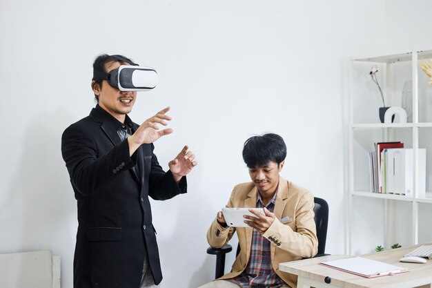 dwóch pracowników testujących okulary VR, dotykających gestami i kontrolujących symulację na tablecie smartfonie