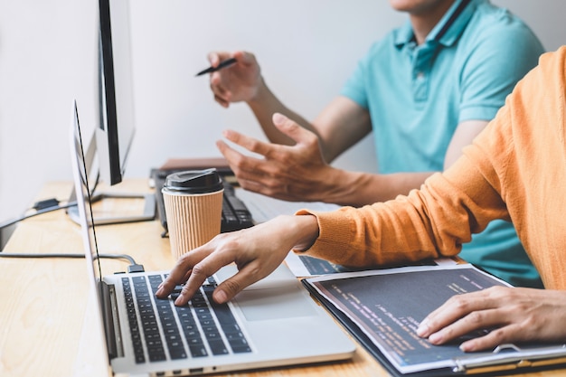 Dwóch profesjonalnych programistów współpracujących i pracujących nad projektem strony internetowej w oprogramowaniu na komputerze stacjonarnym w firmie, kodowanie i kodowanie danych, programowanie za pomocą HTML, PHP i javascript