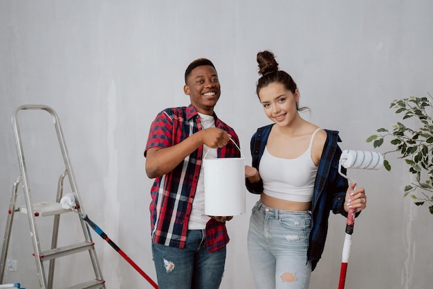 Dwóch przyjaciół remontuje pokój w akademiku, pracują razem malując ściany trzymające wałki