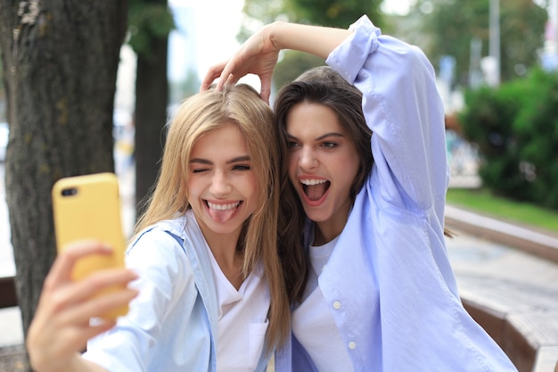 Dwóch przyjaciół roześmiany, ciesząc się wspólnym weekendem i robiąc selfie na tle miasta.