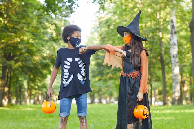 Dwóch przyjaciół w kostiumach na Halloween bawiących się ze sobą w parku