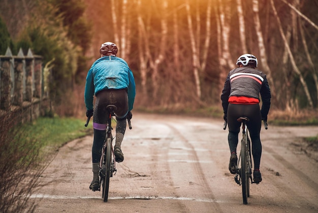 Dwóch rowerzystów z tyłu Nowoczesny rower szutrowy Jazda na rowerze w deszczową pogodę Rowerzysta od tyłu w kasku ochronnym