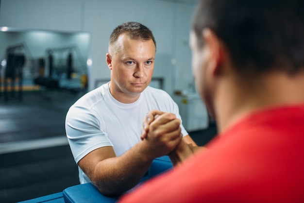 Zdjęcie dwóch siłaczy na rękę przy stole z kołkami, trening