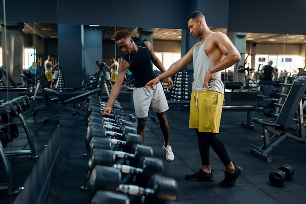 Dwóch sportowców wybierających ciężkie hantle na treningi na siłowni