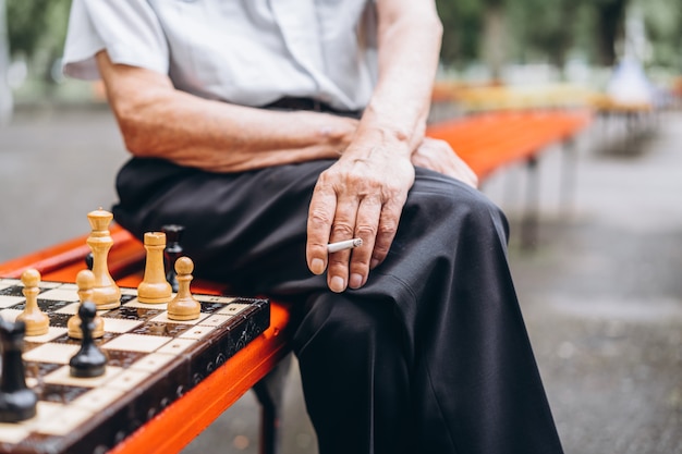 Dwóch starszych mężczyzn gra w szachy na ławce na świeżym powietrzu w parku