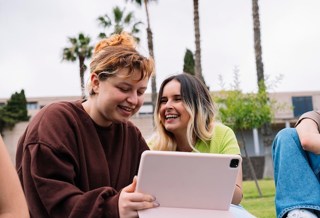Dwóch studentów korzysta z tabletu na kampusowej trawie