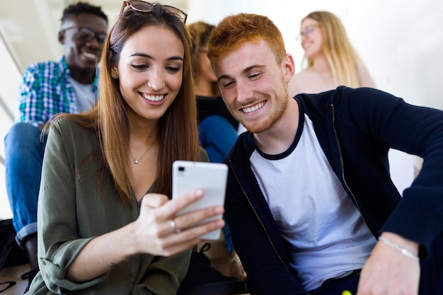 Dwóch studentów korzystających z telefonu komórkowego w uniwersytecie.