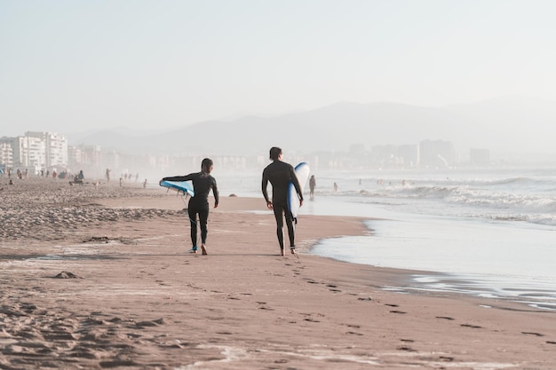 Dwóch surferów spacerujących po plaży La Serena o zachodzie słońca z tyłu