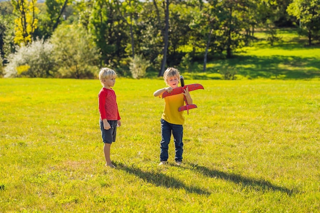 Dwóch szczęśliwych chłopców bawiących się samolocikiem w parku.